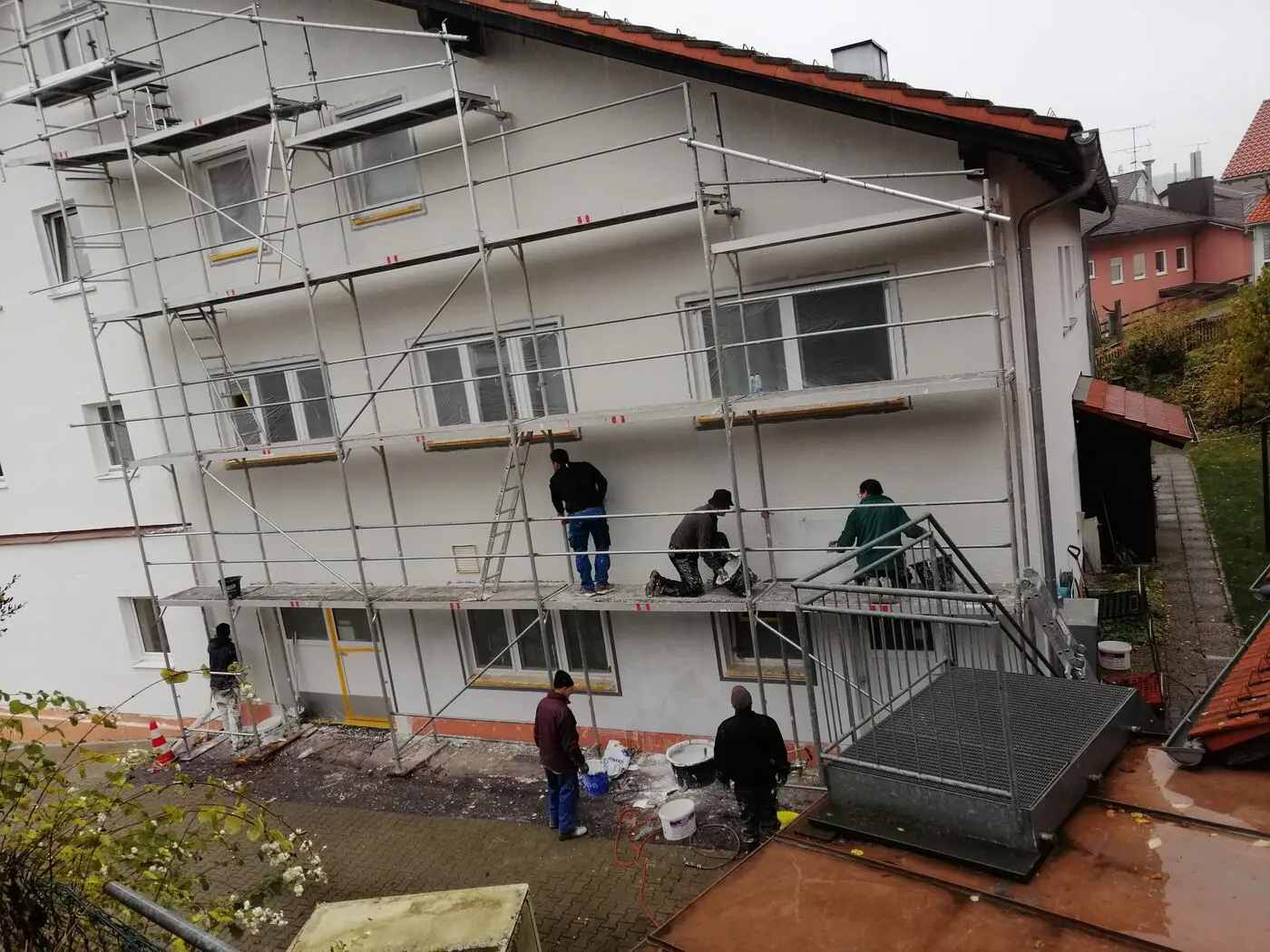 Haus der Lebensgemeinschaft mit Baugerüst, Mitarbeiter renovieren die Fassade